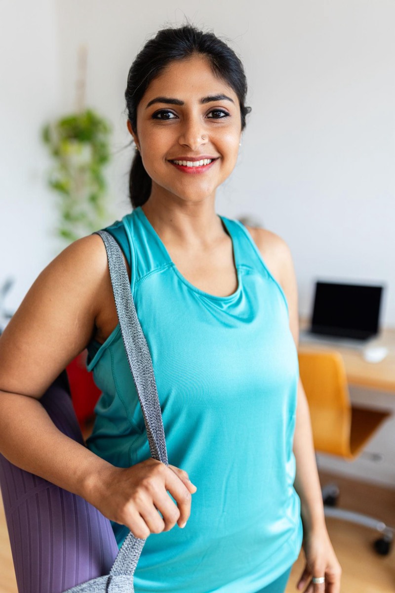 A fitness trainer with a yoga mat over her shoulder