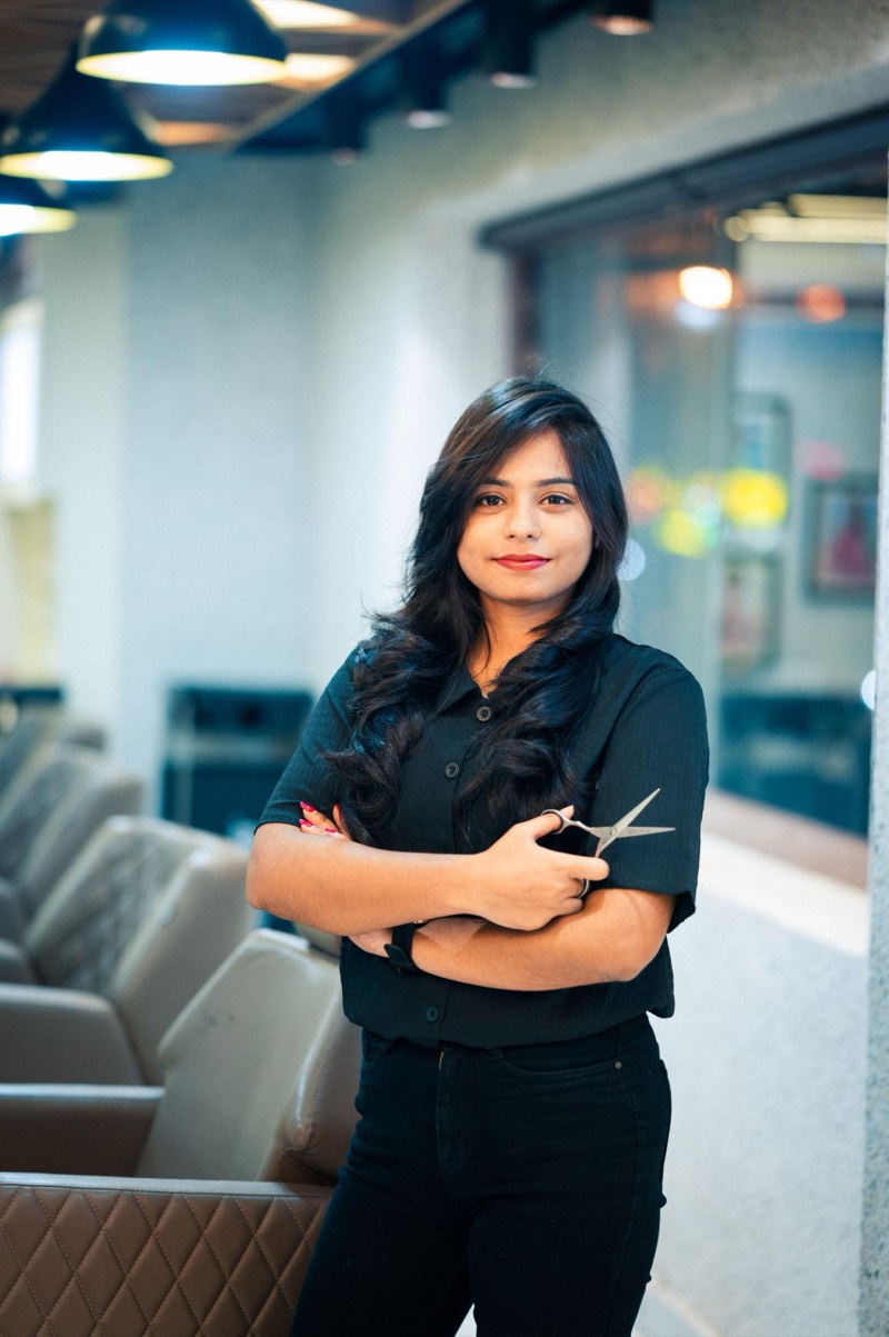 A hair stylist standing in her salon, scissors in hand