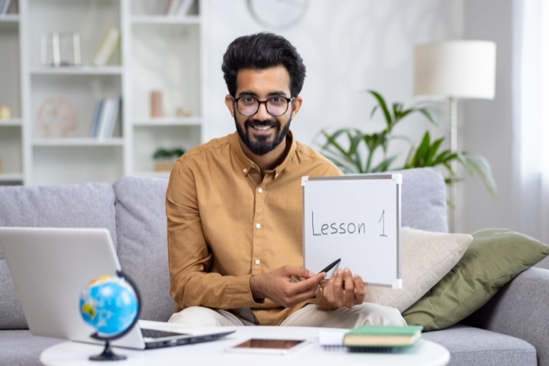 A tutor holding up a whiteboard at the start of an online lesson